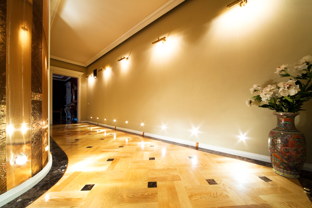 A brightly lit hallway showcasing a mirror-like, polished oak parquet floor with decorative black inlays, newly refinished by West Brompton Floor Sanding.