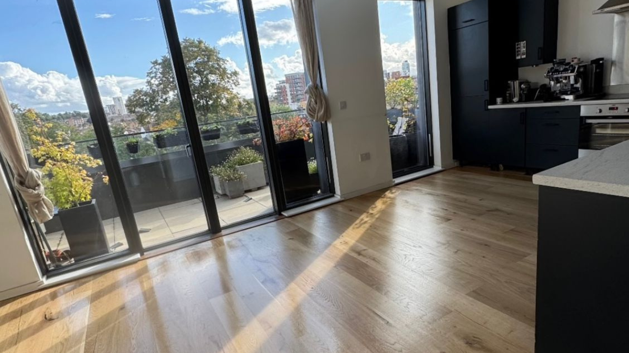 Sunlit engineered oak plank floor in a West Brompton open-plan kitchen/living room after creak fixes and refinishing — Squeaky Repairs Revealed.