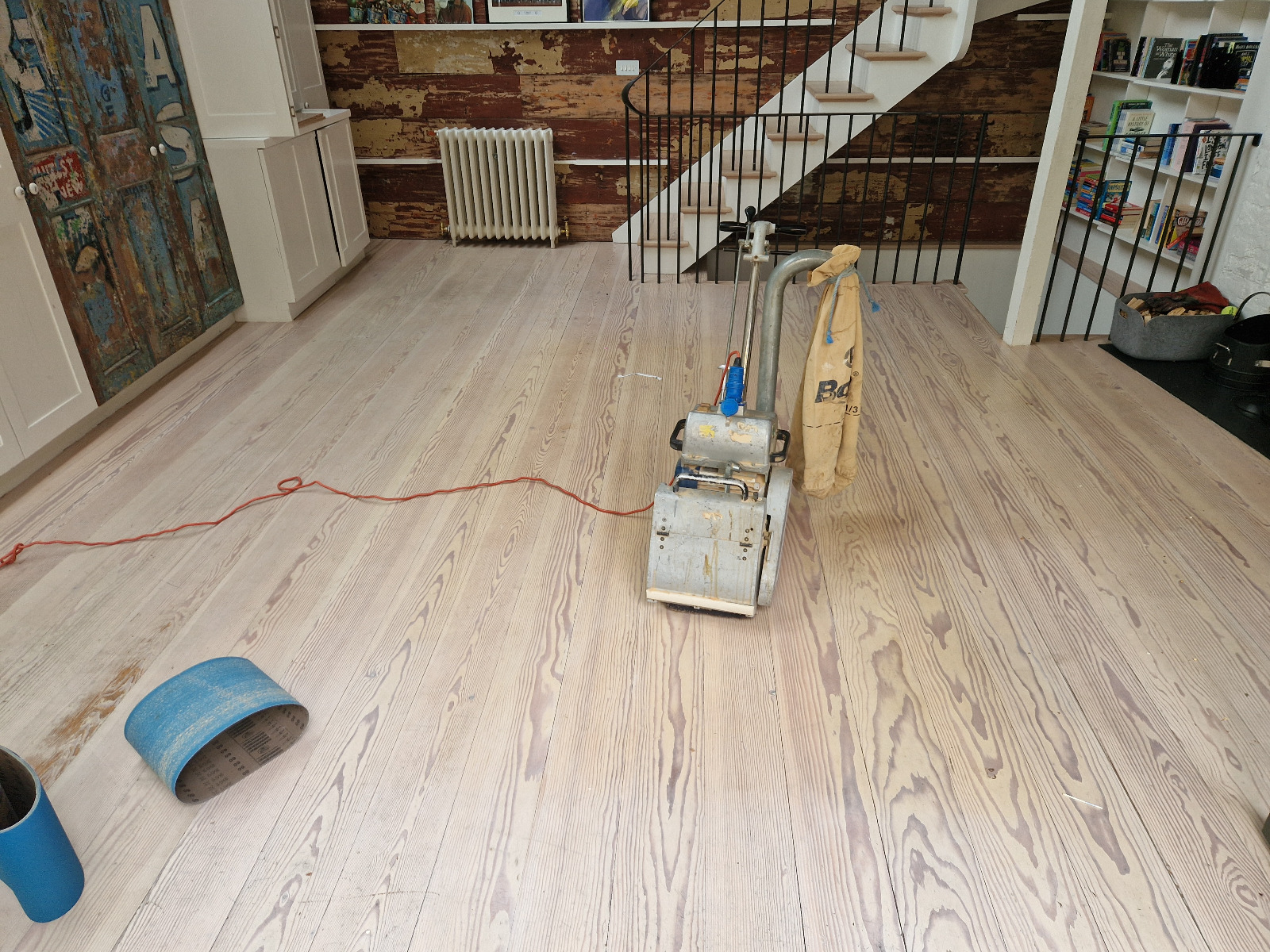 Wood floor sanding in West Brompton living room, pale pine softwood floorboards being sanded with a professional belt sander.