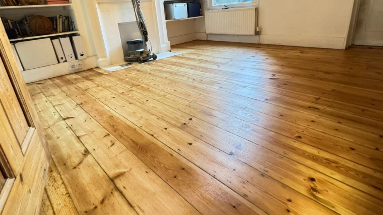 Wood Floor Sanding in West Brompton showing restored solid pine softwood floorboards in a living room with a smooth, honey-toned finish.