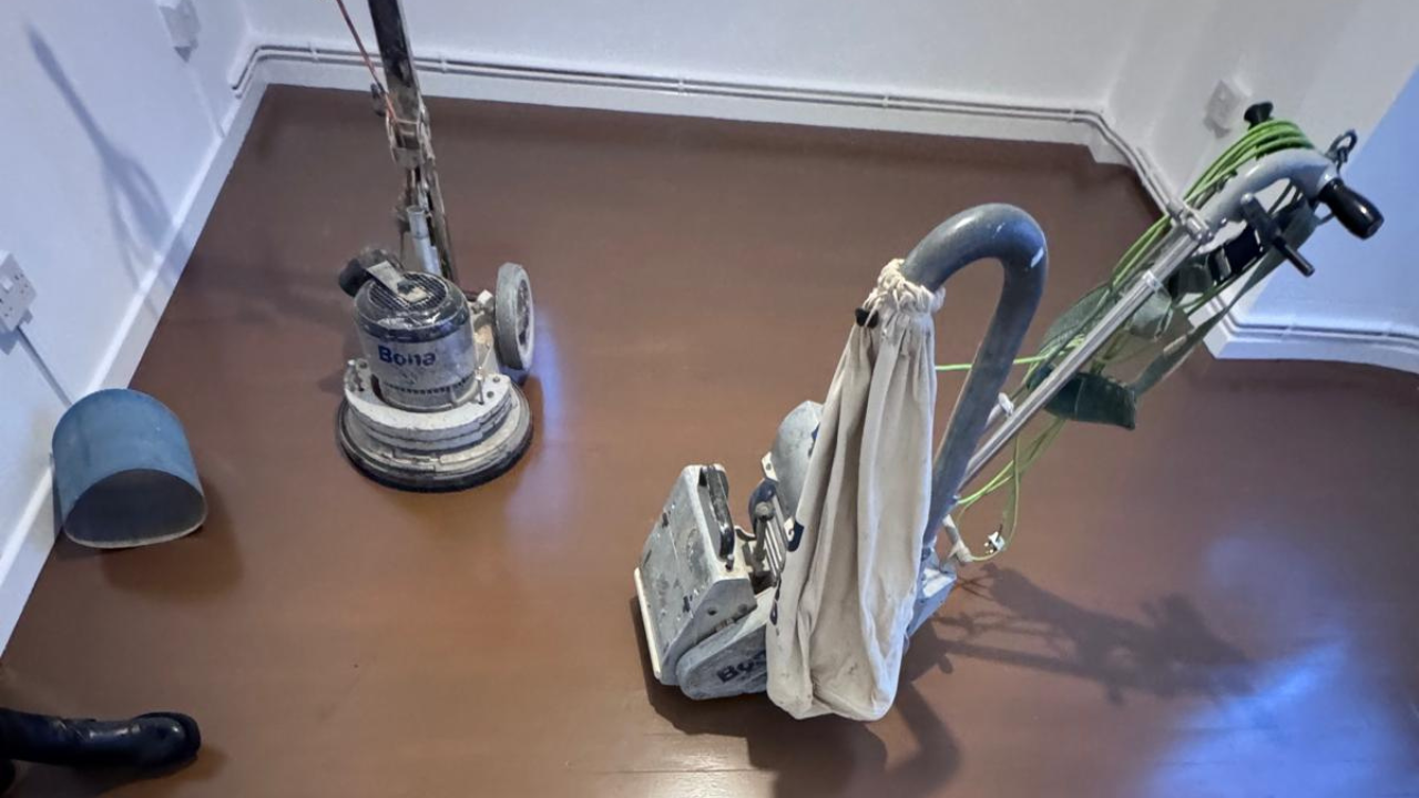 Hardwood Floor Sanding in West Brompton on a solid oak hardwood floor, showing professional sanding machines set up in a small room ready to refinish the brown painted boards.